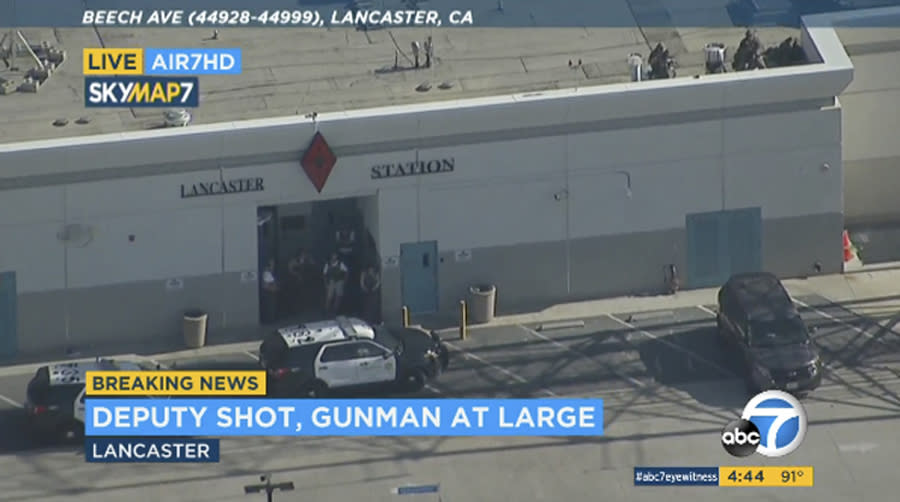 This photo taken from video provided by KABC-TV shows the outside of a Los Angeles County sheriff's station in Lancaster, Calif., on Wednesday, Aug. 21, 2019. The mayor of Lancaster says a deputy shot and wounded outside the station is going to be Okay after he visited him at the hospital. Authorities are searching for the shooter in buildings surrounding the station where the deputy was hit in the shoulder while standing in the parking lot Wednesday afternoon. (KABC-TV via AP)