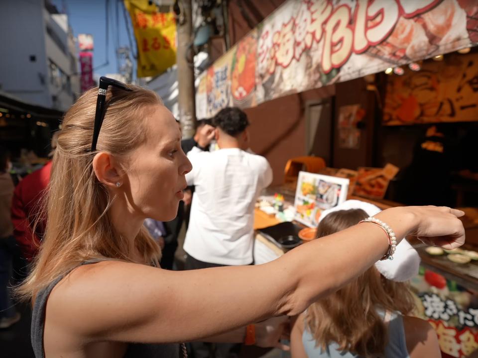 phil's wife buying something from a fish market in tokyo japan