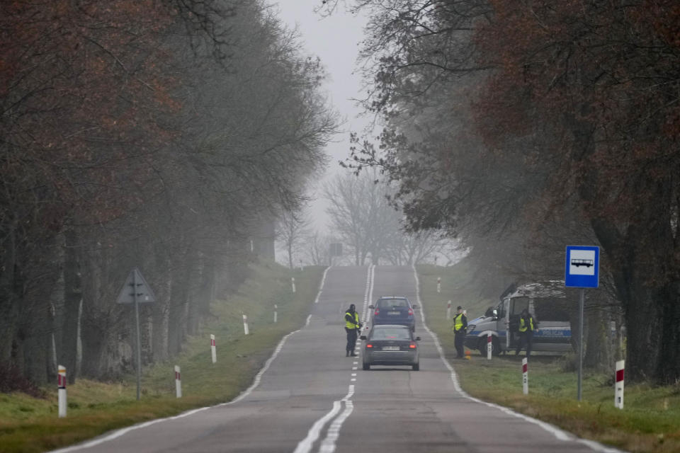 Polish police officers check cars near the border to Belarus, that was closed because of a large group of migrants camping in the area on the Belarus side who had tried to illegally push their way into Poland and into the European Union, in Kuznica, Poland, Thursday, Nov. 11, 2021. (AP Photo/Matthias Schrader)
