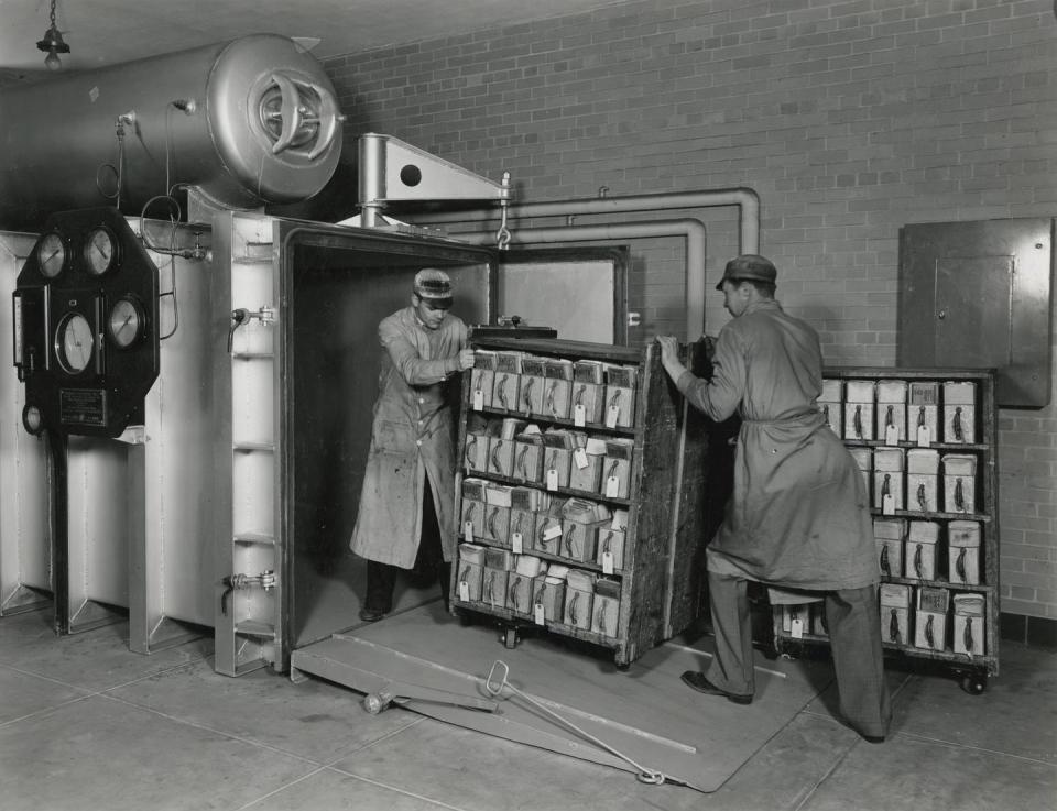 National Archives workers push a cart of Veterans Administration records into a vacuum chamber for fumigation in June 1936.