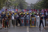 Anti-coup protesters standing behind a line of makeshift shields demonstrate in Yangon, Myanmar Tuesday, March 9, 2021. Demonstrators in Myanmar's biggest city came out Monday night for their first mass protests in defiance of an 8 p.m. curfew, seeking to show support for an estimated 200 students trapped by security forces in a small area of one neighborhood. (AP Photo)