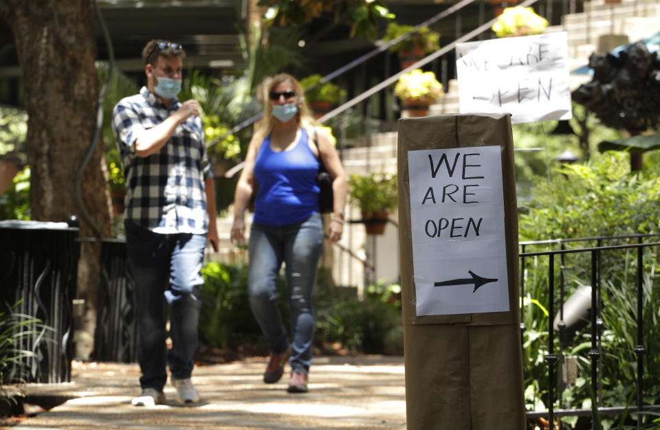 Unas personas con mascarillas caminan frente a un negocio que reabrió en San Antonio, Texas, el jueves 14 de mayo de 2020, luego de que las autoridades del estado redujeron las medidas implementadas por la pandemia de coronavirus. (AP Foto/Eric Gay)