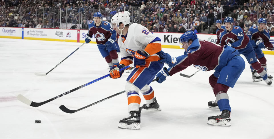 New York Islanders center Kyle Palmieri, left, struggles to control the puck as Colorado Avalanche defenseman Bowen Byram covers in the second period of an NHL hockey game Tuesday, Jan. 2, 2024, in Denver. (AP Photo/David Zalubowski)