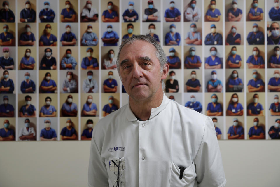 Dr. Philippe Montravers poses in front of a collection of portraits of medical staff at Bichat Hospital, AP-HP, in Paris, Wednesday, Dec. 2, 2020. One of the biggest hospitals in Paris, Bichat Hospital, this month reopened all 22 of its operating rooms. It is once again performing surgeries that were stopped during virus surges that pushed France's death toll past 55,000. (AP Photo/Francois Mori)