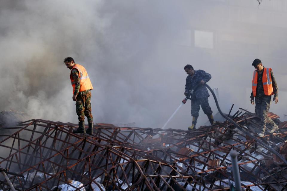 Firefighters spray a smoldering ruin.