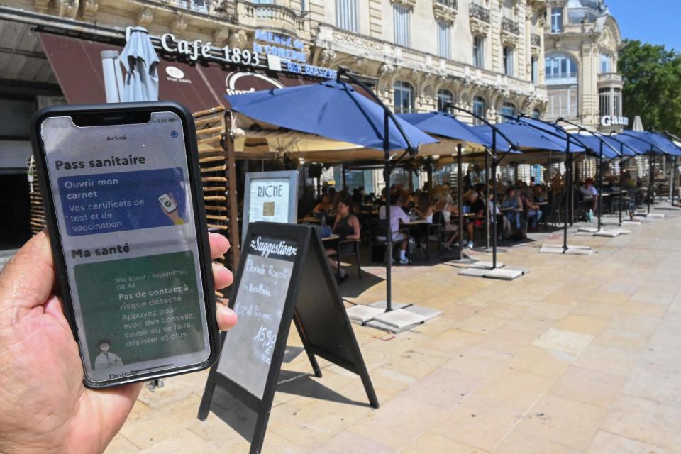 A man shows a digital sanitary pass document on his smartphone in front of a restaurant in southern France on Wednesday. France began enforcing a COVID-19 pass in cafes, restaurants and trains.