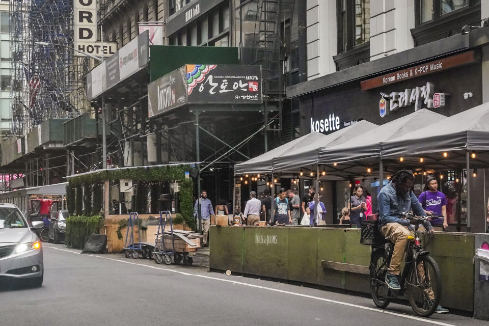 Pandemic-era outdoor dining extensions, left, sit on street parking spaces outside restaurants in mid-town Manhattan, Tuesday Aug. 8, 2023, New York City's roadway dining sheds, a pandemic innovation, are coming under new rules for design and seasonality. (AP Photo/Bebeto Matthews)