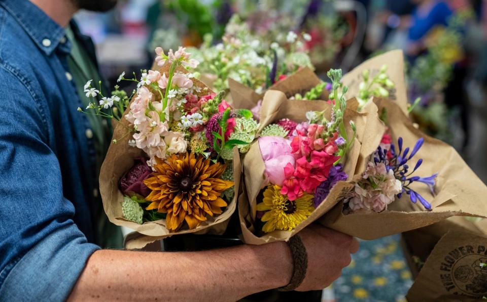 Brent Grant, co-owner of The Flower Project, holds a bucket full of flower bouquets grown on his farm during the Royal Oak Farmers Market in Royal Oak on Saturday, June 29, 2024.