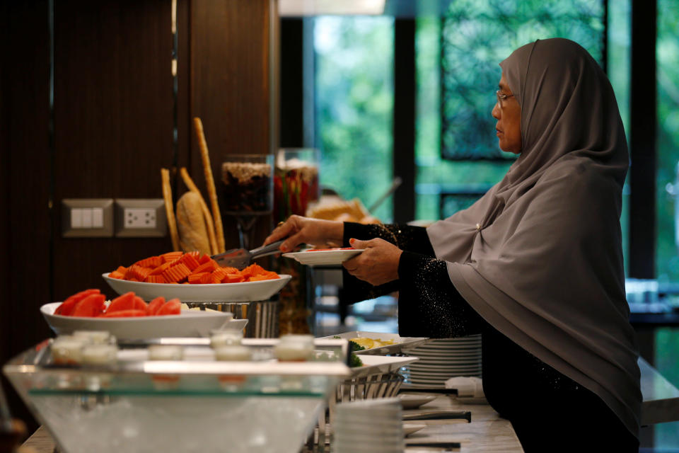 A Muslim visitor takes food from a platter for her breakfast at the Al Meroz hotel in Bangkok