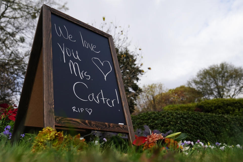 Bouquets of flowers and a chalkboard sign that reads "We love you Mrs. Carter" is displayed near the front of The Carter Center, Monday, Nov. 20, 2023, in Atlanta. Rosalynn Carter’s tiny hometown of Plains, is mourning the death of the former U.S. first lady and global humanitarian, who died Sunday at 96. (AP Photo/Brynn Anderson)