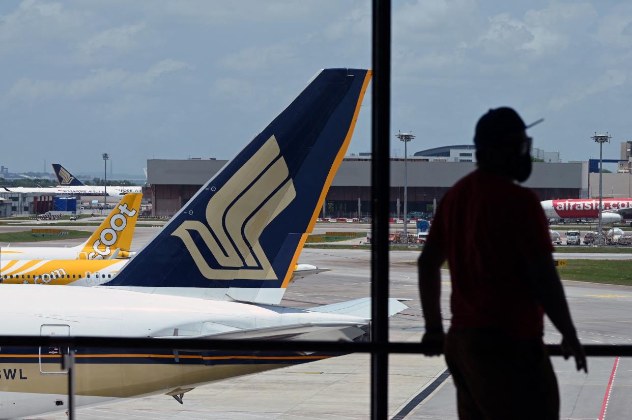 A Singapore Airlines plane is parked besides a Scoot passenger plane on the terminal tarmac at Changi International Airport in Singapore on March 15, 2021. (Photo by Roslan RAHMAN / AFP) (Photo by ROSLAN RAHMAN/AFP via Getty Images)