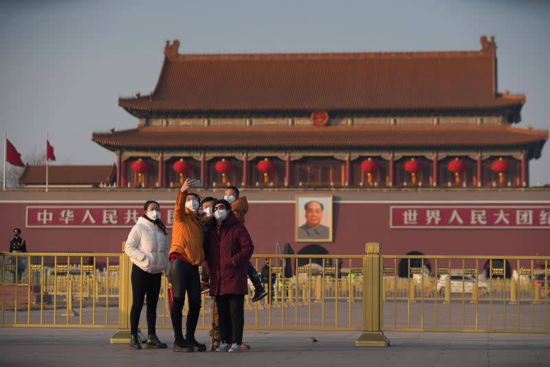 Visitors wearing masks take selfies in front of the Tiananmen Gate, as the country is hit by an epidemic of the new coronavirus, in Beijing