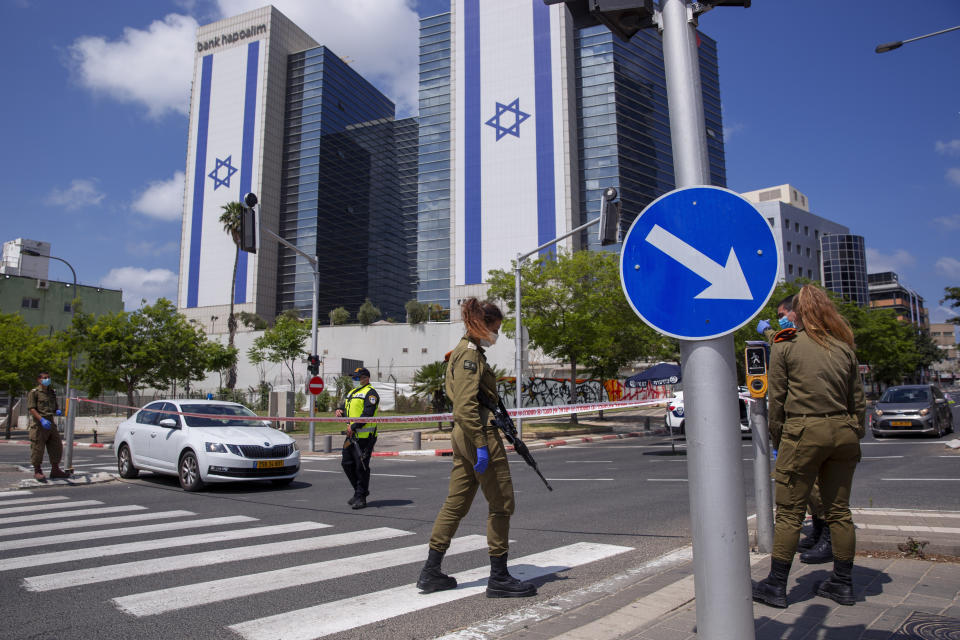 Israeli police officer and Israeli soldiers wear face masks and gloves at a roadblock during a lockdown following government measures to help stop the spread of the coronavirus, on Israel's 72nd Independence Day, in Tel Aviv, Israel, Wednesday, April 29, 2020. (AP Photo/Oded Balilty)