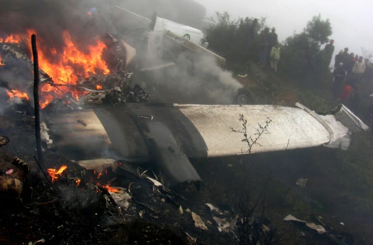 Bystanders look at the wreckage of a Yeti Airlines aircraft burning at the Tenzing-Hillary Airport in Lukla in 2008