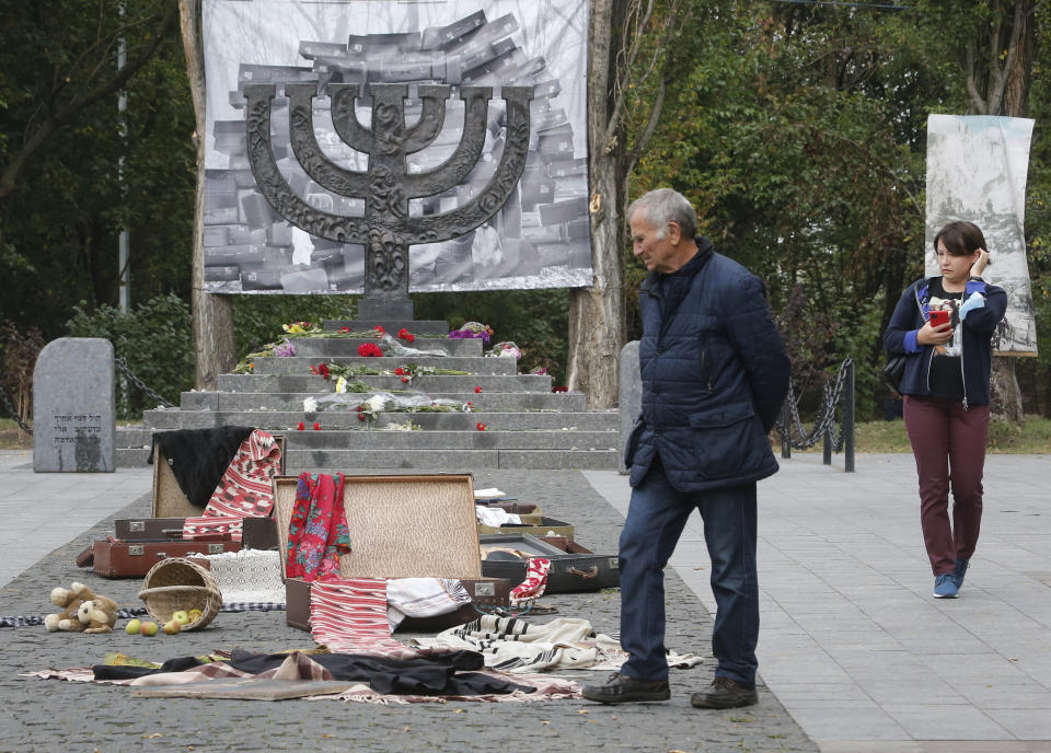 People look an art installation to mark 79th anniversary of the 1941 Babi Yar massacre at a menorah monument close to a Babi Yar ravine where tens of thousands of Jews were killed during WWII, in Kyiv, Ukraine, Tuesday, Sept. 29, 2020. Ukraine marked the 79th anniversary of the 1941 Babi Yar massacre. (AP Photo/Efrem Lukatsky)