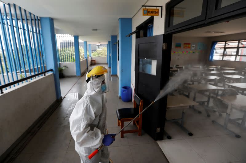 An Indonesian Red Cross personnel wearing a protective gear sprays disinfectant inside a classroom of a school, in Jakarta