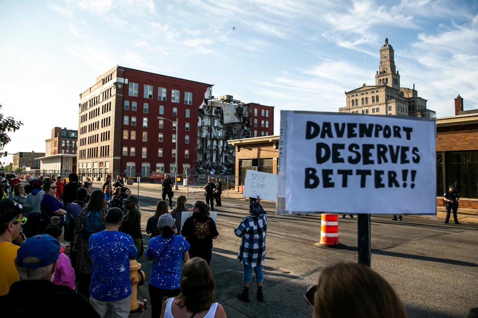 Davenport police officers form a line opposite protesters who were advocating for search efforts to continue Tuesday near the site of an apartment building that partially collapsed in Davenport.