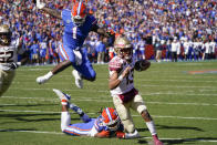 Florida State quarterback Jordan Travis (13) scrambles for a 9-yard touchdown run past Florida linebacker Brenton Cox Jr. (1) and linebacker Ty'Ron Hopper (28) during the first half of an NCAA college football game, Saturday, Nov. 27, 2021, in Gainesville, Fla. (AP Photo/John Raoux)