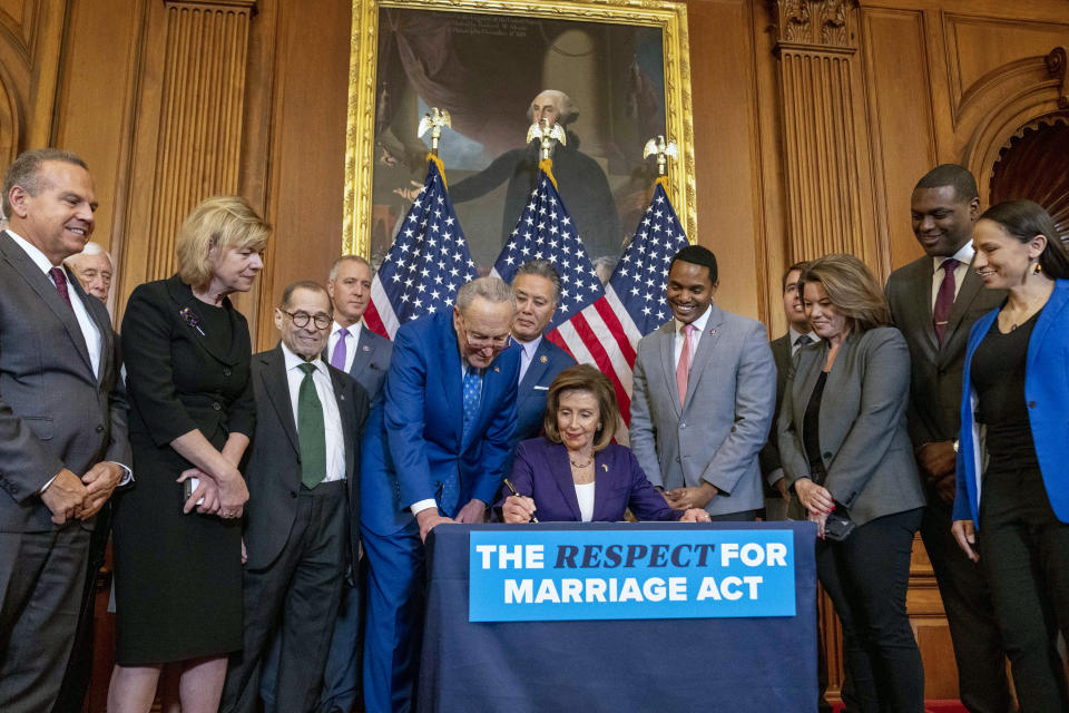House Speaker Nancy Pelosi of Calif., accompanied by Senate Majority Leader Sen. Chuck Schumer of N.Y., center left, and other members of Congress, signs the H.R. 8404, the Respect For Marriage Act, on Capitol Hill in Washington, Thursday, Dec. 8, 2022. (AP Photo/Andrew Harnik)