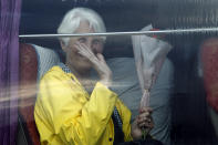 A passenger waves from a bus after she disembarked from the MS Westerdam, owned by Holland America Line, at the port of Sihanoukville, Cambodia, Friday, Feb. 14, 2020. Passengers finally disembarked on Friday from the cruise ship allowed to dock in Cambodia following two weeks of being stranded at sea after being refused entry by four Asian governments because of virus fears. (AP Photo/Heng Sinith)