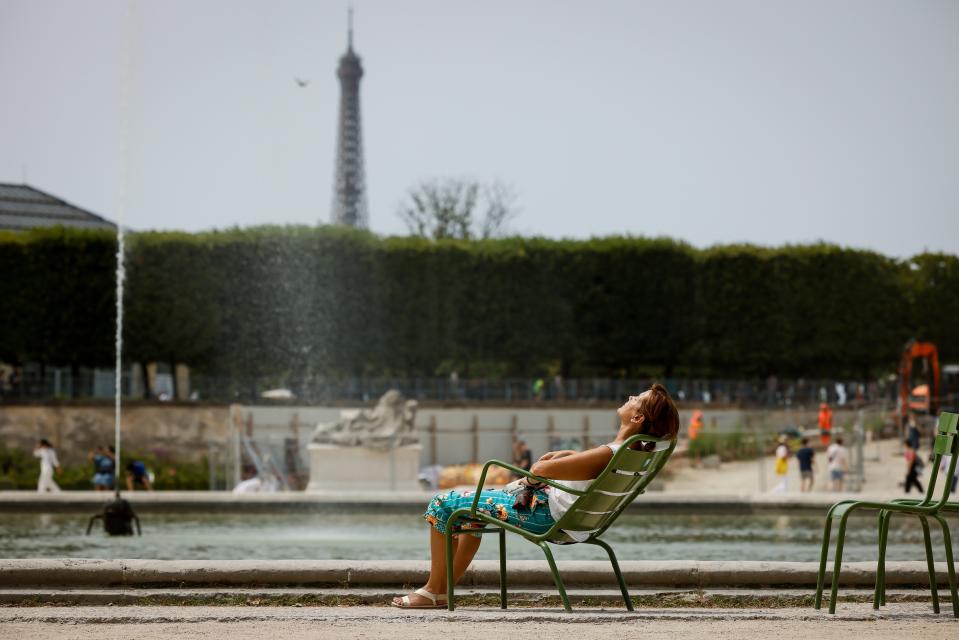 A woman enjoys the sun in the Tuileries gardens, Paris (AP)