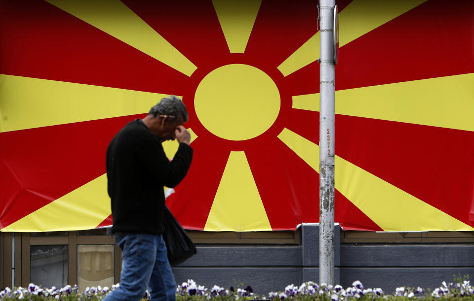 A man walks past the national flag set in a street in Skopje, North Macedonia, Friday, April 19, 2019. North Macedonia holds the first round of presidential elections on Sunday, a vote seen as key test for the center-left government's survival in a society deeply divided after the country changed its name to end a decades-old dispute with neighboring Greece over use of the term "Macedonia". (AP Photo/Boris Grdanoski)
