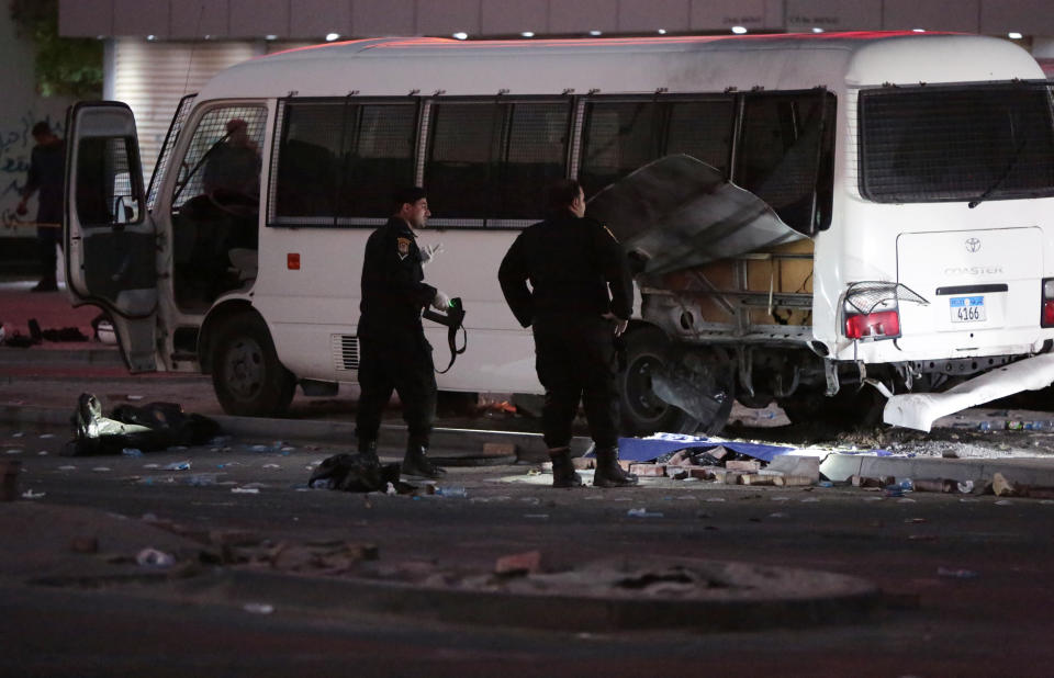 Police officers inspect damage to a bus in Dih, on the edge of the capital of Manama, Bahrain, Friday, Feb. 14, 2014. An explosion rocked a bus carrying police in Bahrain on Friday, while security forces used tear gas in clashes with anti-government protesters on the third anniversary of an uprising in the small Gulf island nation. (AP Photo/Hasan Jamali)