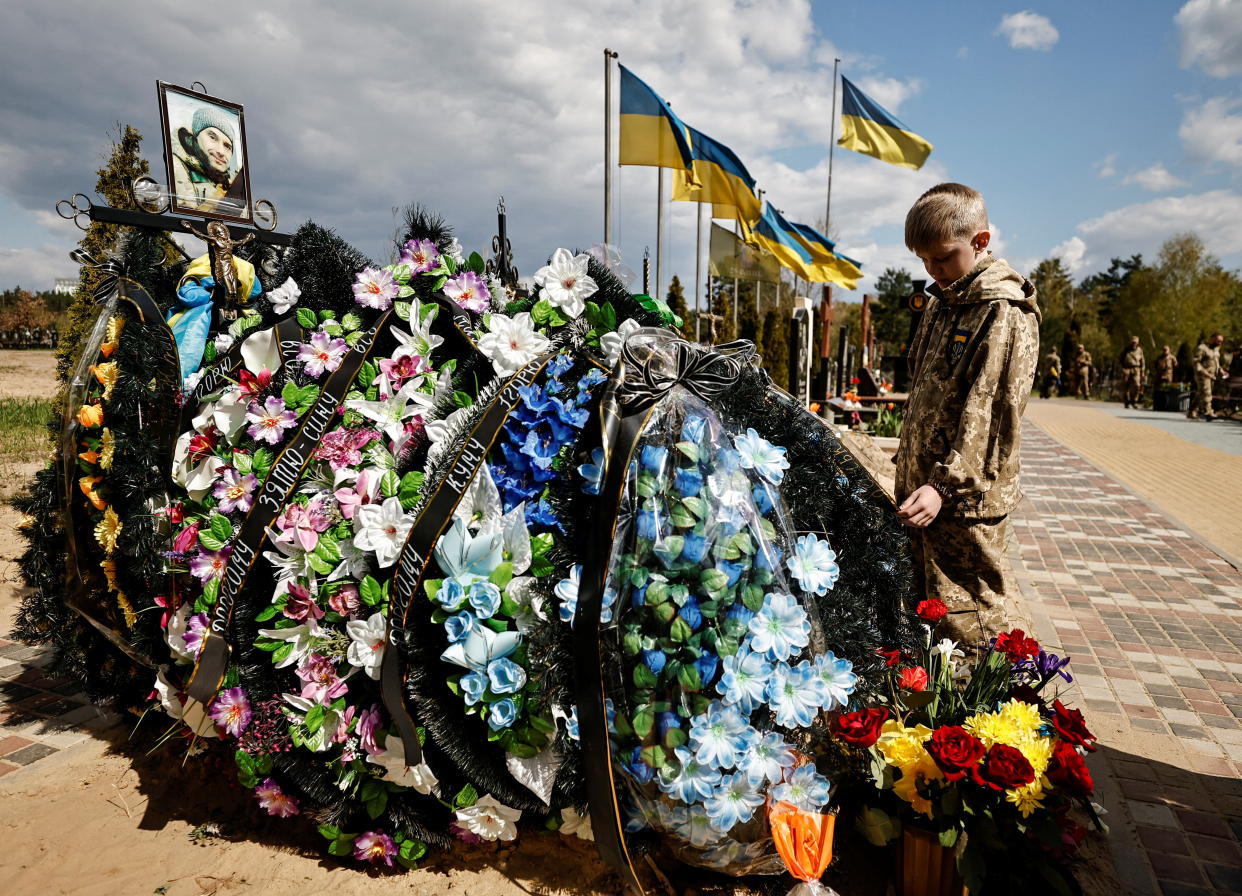 A 10-year-old boy stands by his father's grave.