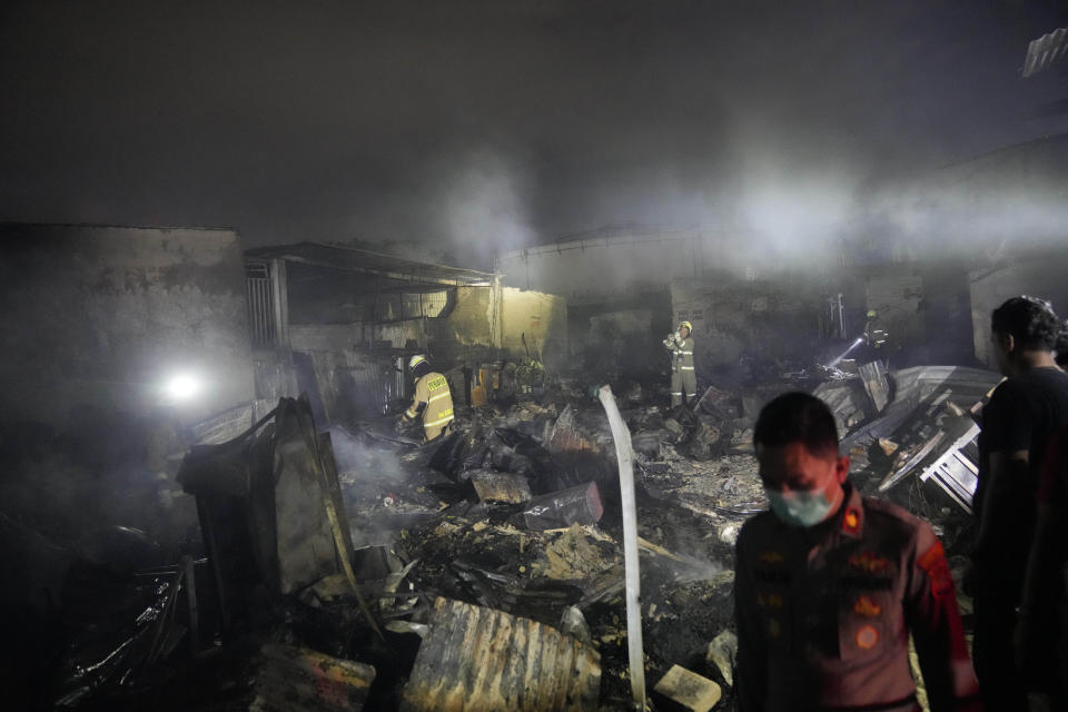 Firefighters inspect the ruins of houses destroyed in a fire in Jakarta, Indonesia, Friday, March 3, 2023. A large fire broke out at a fuel storage depot in Indonesia’s capital on Friday, killing several people, injuring dozens of others and forcing the evacuation of thousands of nearby residents after spreading to their neighborhood, officials said. (AP Photo/Dita Alangkara)