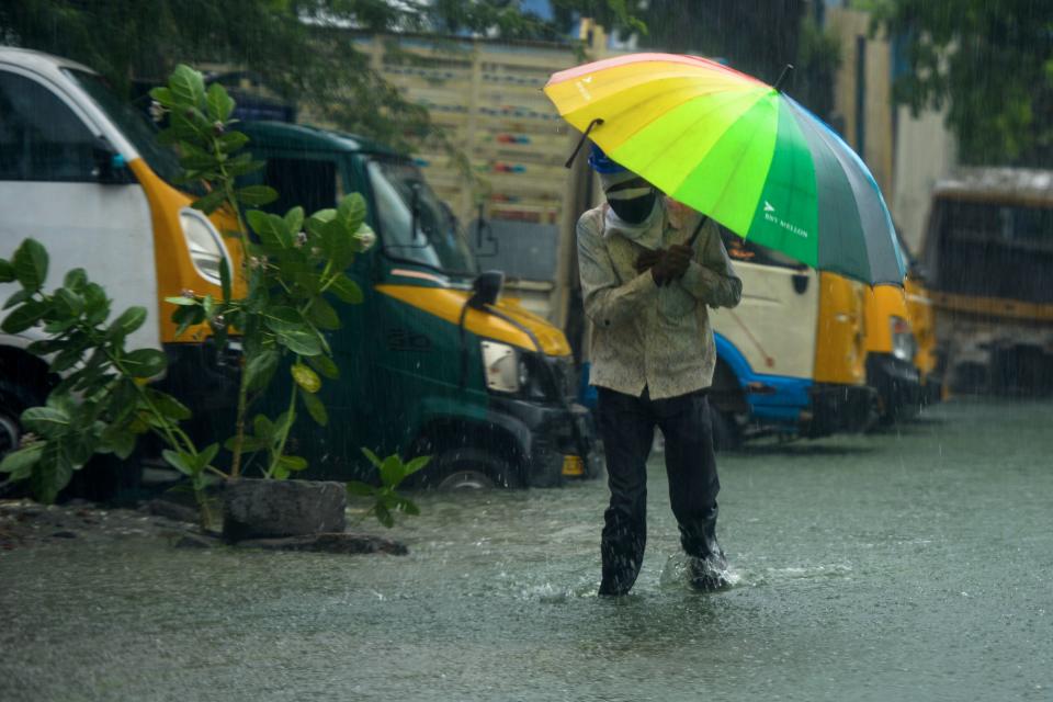 A man walks along a flooded street under heavy rains in Chennai as cyclone Nivar approaches on November 25, 2020. (Photo by ARUN SANKAR/AFP via Getty Images)