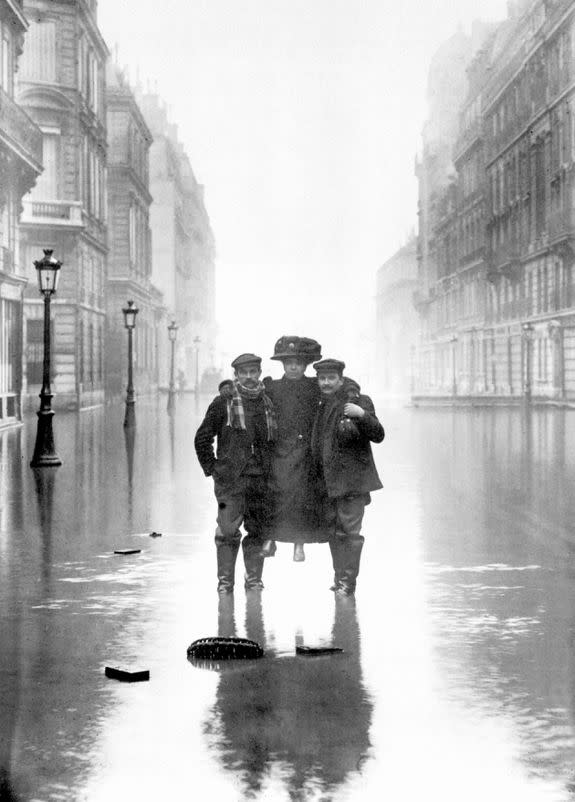 Two men carrying a woman through the flooded streets of Paris.