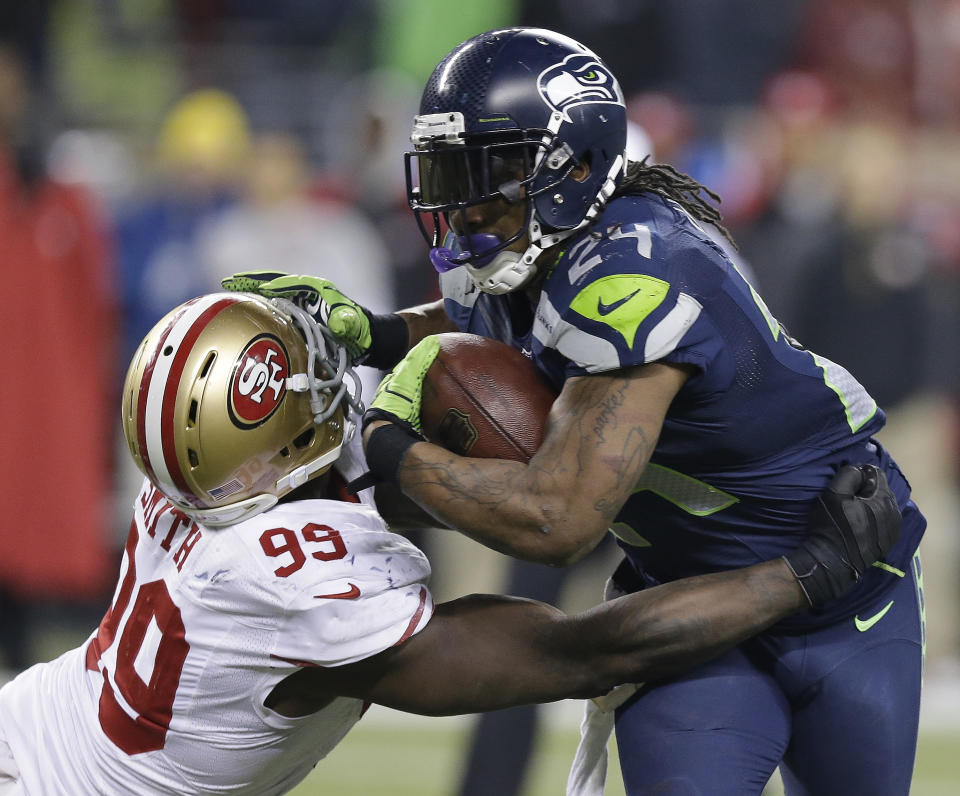 Seattle Seahawks' Marshawn Lynch tries to run past San Francisco 49ers' Aldon Smith during the second half of the NFL football NFC Championship game Sunday, Jan. 19, 2014, in Seattle. (AP Photo/Elaine Thompson)