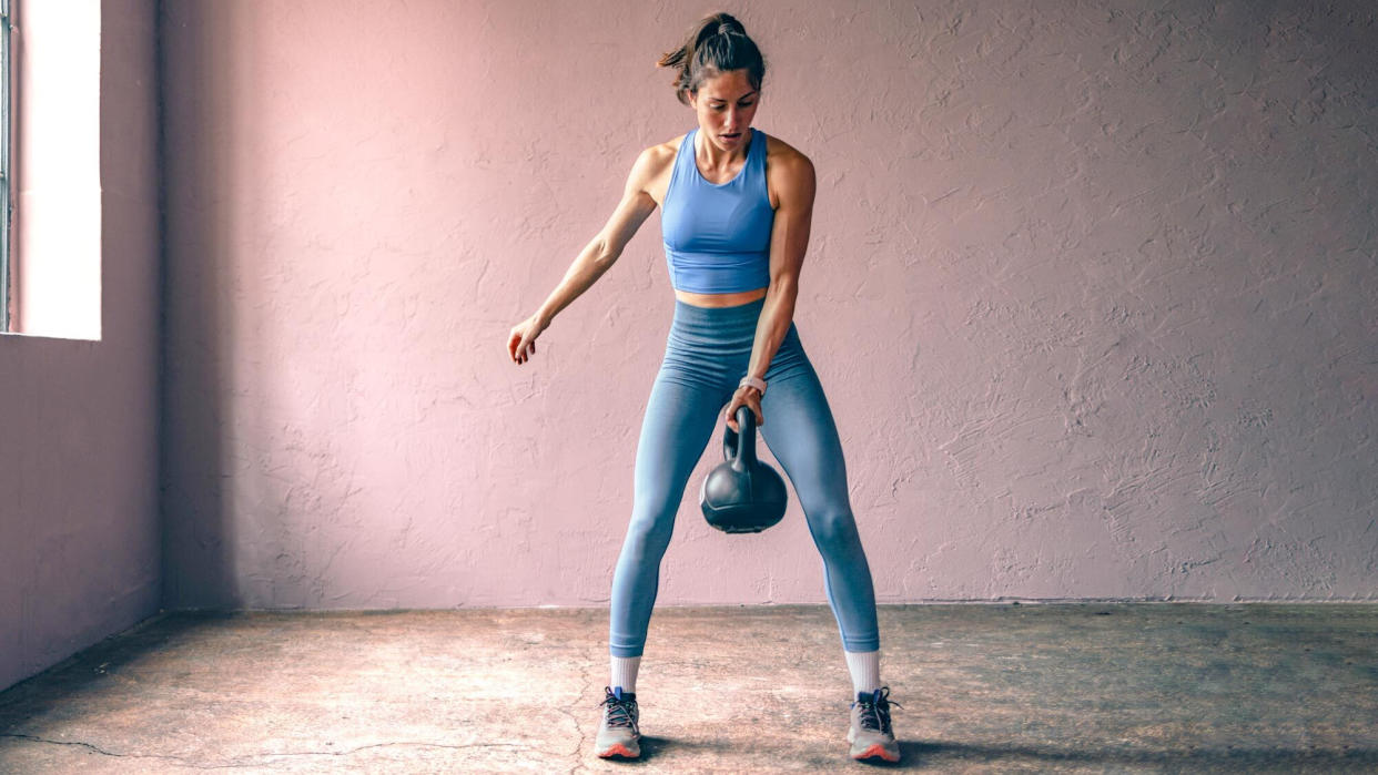  Woman performing a single-arm kettlebell swing. 