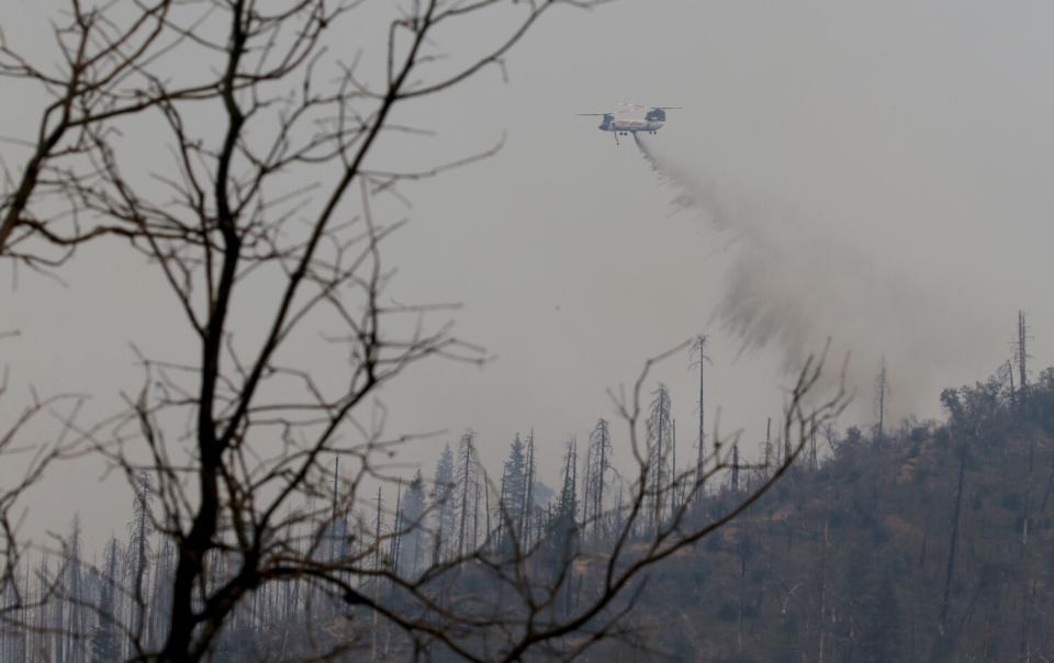 A firefighting helicopter drops water on the Oak fire in a mountainous area near Mariposa on Tuesday.