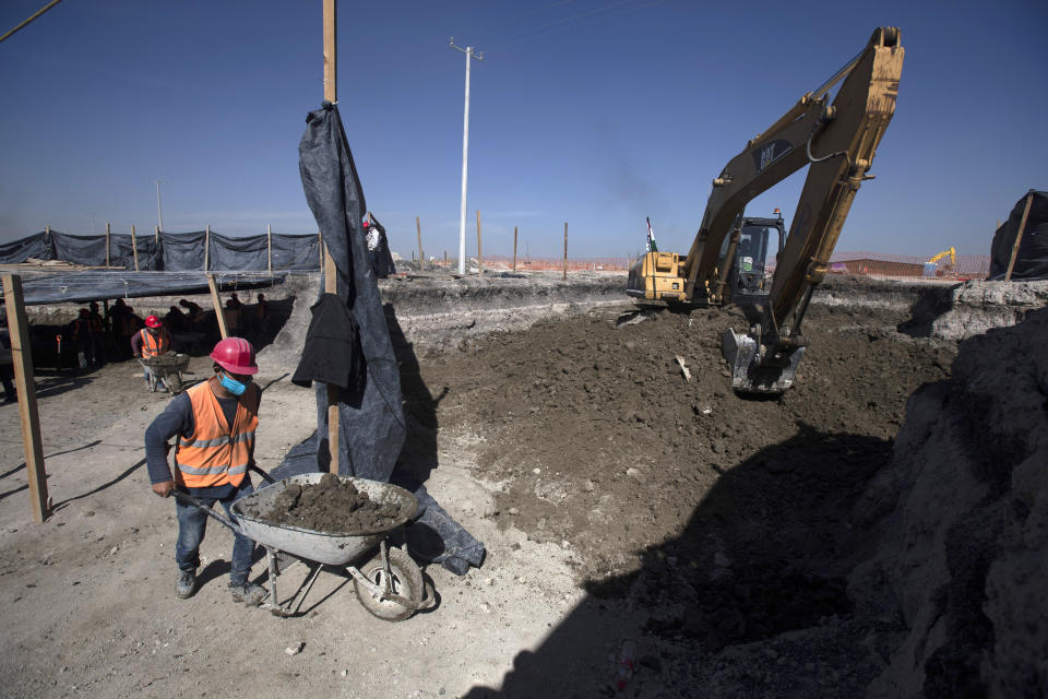 Workers bring out wheelbarrows of dirs as paleontologists work to preserve the skeleton of a mammoth that was discovered at the construction site of Mexico City’s new airport in the Santa Lucia military base, Mexico, Thursday, Sept. 3, 2020. The paleontologists are busy digging up and preserving the skeletons of mammoths, camels, horses, and bison as machinery and workers are busy with the construction of the Felipe Angeles International Airport by order of President Andres Manuel Lopez Obrador. (AP Photo/Marco Ugarte)