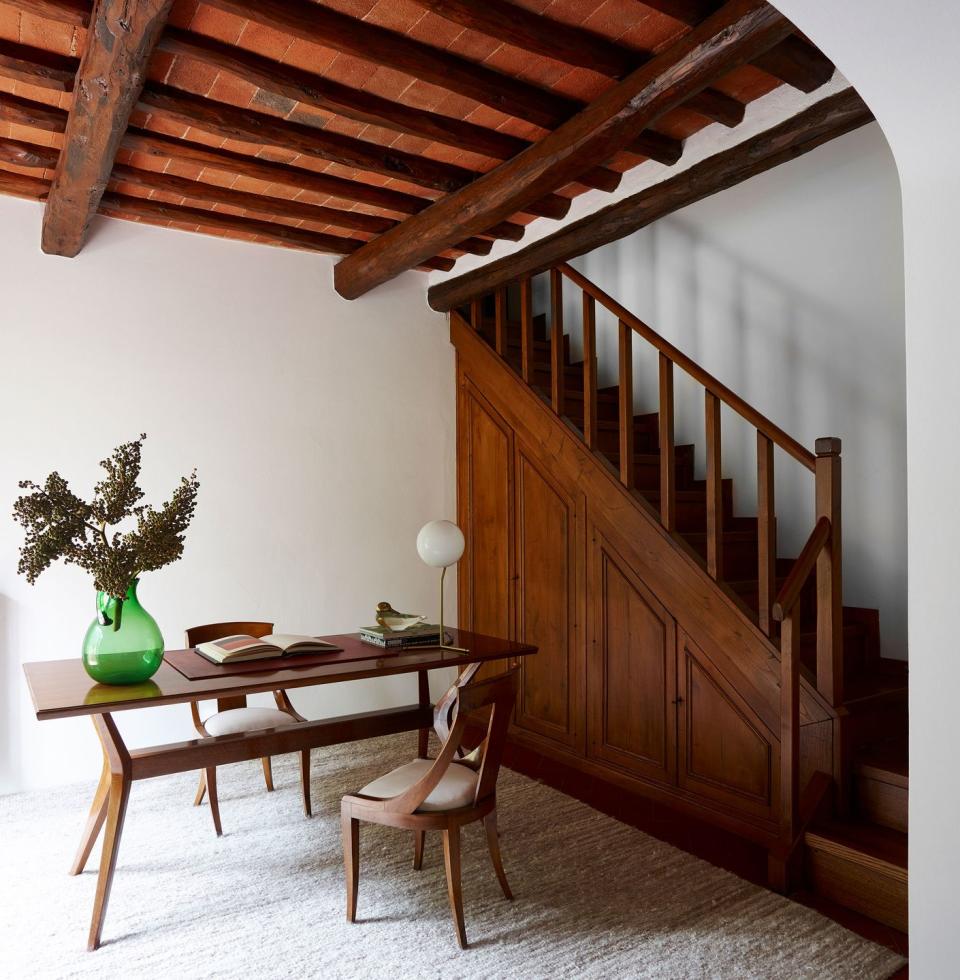 small table with green glass vase next to a beautiful wooden staircase