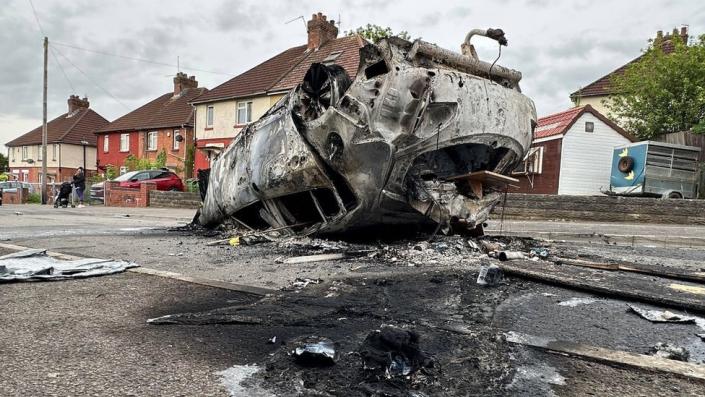 A burnt out car upside down on a road