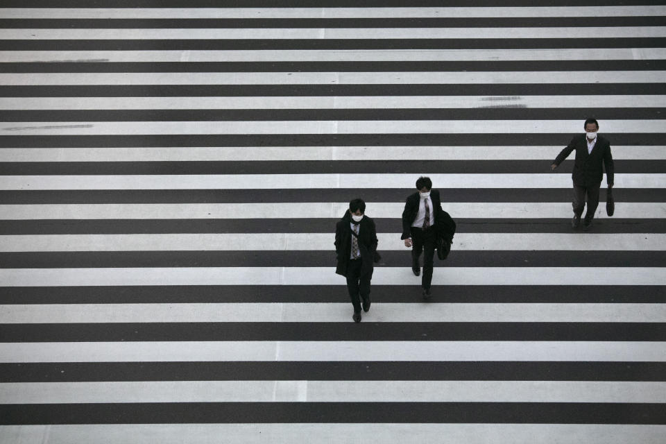 Commuters wearing masks walk across a pedestrian crosswalk Wednesday, Feb. 26, 2020, in Tokyo. At a government task force meeting Wednesday on the virus outbreak, Prime Minister Shinzo Abe said he was asking organizers to cancel or postpone major sports or cultural events over the next two weeks. (AP Photo/Jae C. Hong)