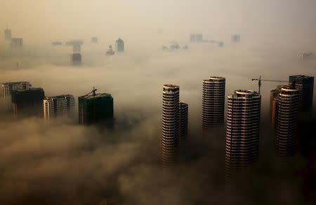 Buildings in construction are seen among mist during a hazy day in Rizhao, Shandong province, China, October 18, 2015. REUTERS/Stringer