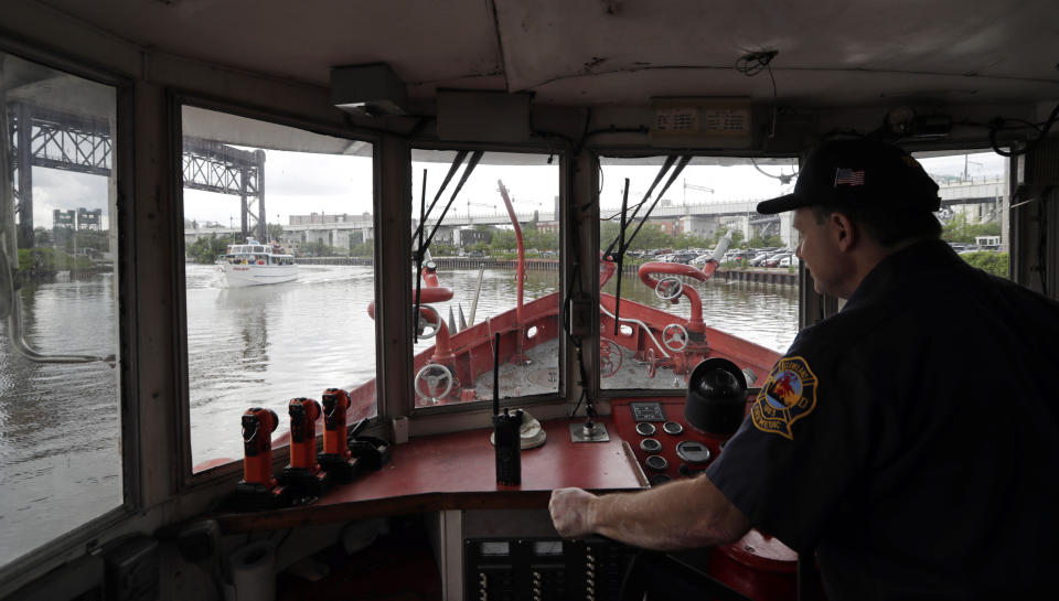 Firefighter Greg Geracioti maneuvers the Anthony J. Celebrezze down the Cuyahoga River, Thursday, June 13, 2019, in Cleveland. The fire boat extinguished hot spots on a railroad bridge torched by burning fluids and debris on the Cuyahoga River in 1969. (AP Photo/Tony Dejak)