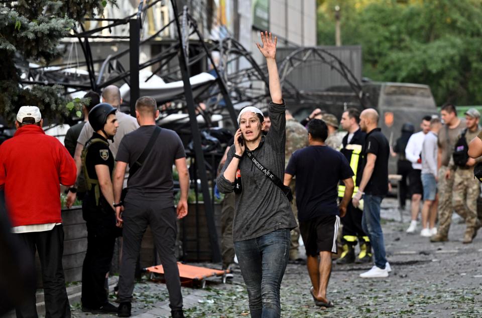 A wounded woman waves while speaking on the phone as rescuers and volunteers work to rescue people from under rubble (AFP via Getty Images)