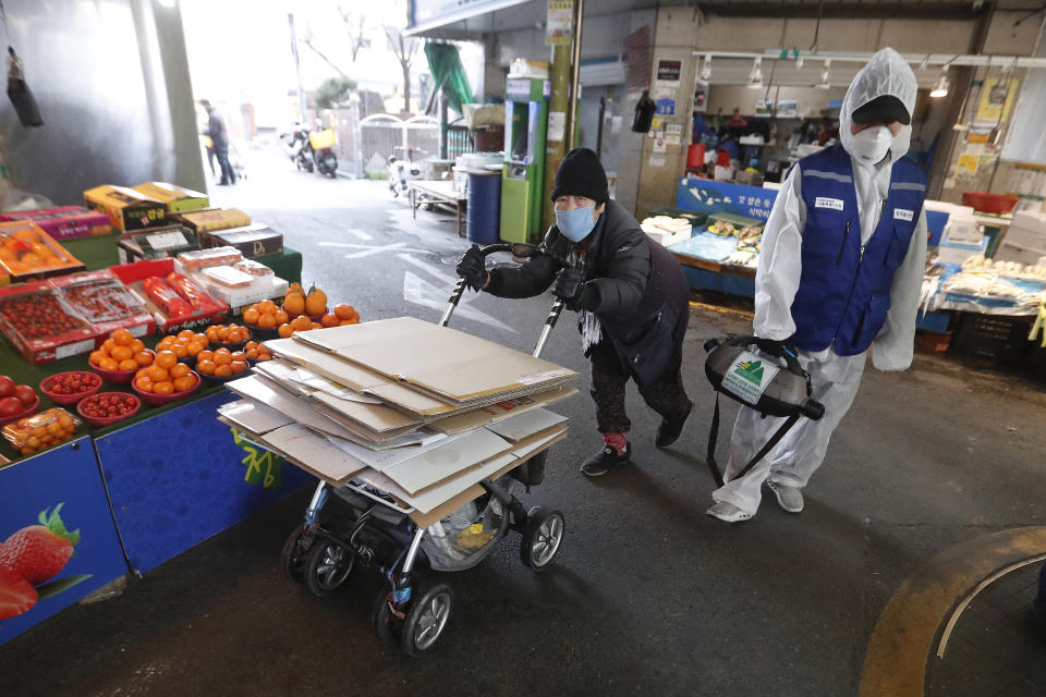 A workers wearing protective gears sprays disinfectant as a precaution against the coronavirus at a market in Seoul, South Korea, Monday, Feb. 24, 2020. South Korean President Moon Jae-in said his government had increased its anti-virus alert level by one notch to “Red,” the highest level. It allows for the temporary closure of schools and reduced operation of public transportation and flights to and from South Korea. (AP Photo/Ahn Young-joon)