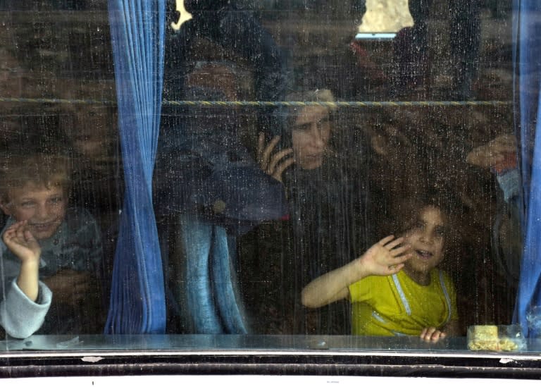 Buses carrying Syrians evacuated from besieged government-held Fuaa and Kafraya arrive at Aleppo's Ramousseh crossing on April 21, 2017