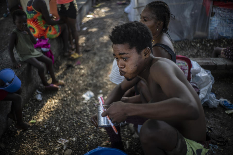 A man rinses his mouth after brushing his teeth at the Hugo Chavez public square transformed into a refuge for families forced to leave their homes due to clashes between armed gangs in Port-au-Prince, Haiti, Thursday, Oct. 20, 2022. (AP Photo/ Ramon Espinosa)