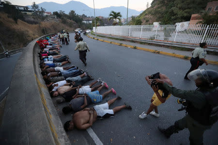 People detained by security forces lie on the street after looting broke out during an ongoing blackout in Caracas, Venezuela, March 10, 2019. REUTERS/Ivan Alvarado