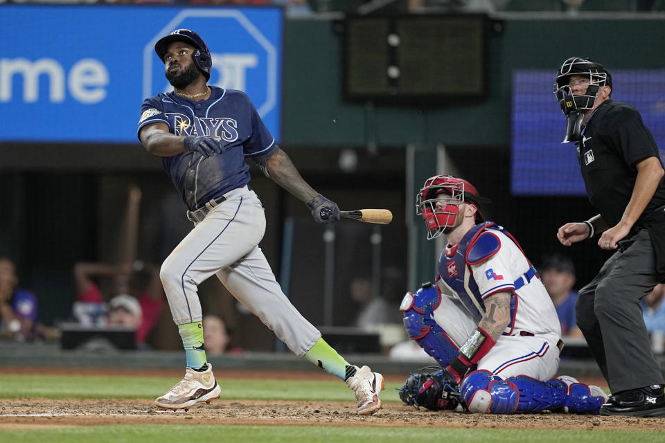 Tampa Bay Rays' Randy Arozarena follows through on a solo home run next to Texas Rangers catcher Jonah Heim and umpire Cory Blaser during the eighth inning of a baseball game Tuesday, July 18, 2023, in Arlington, Texas. (AP Photo/Tony Gutierrez)
