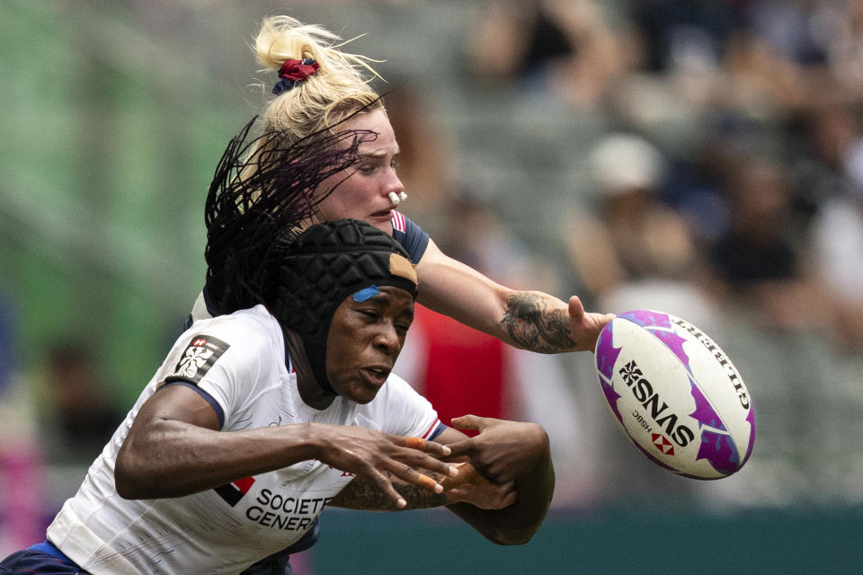 FILE - Seraphine Okemba, foreground, of France is tackled as Samantha Sullivan of the United States fights for the ball during the women semifinal match in the Hong Kong Sevens rugby tournament in Hong Kong, Sunday, April 7, 2024. The first women's professional rugby league in the United States is targeting 2025 for its start with six to eight 30-player teams, organizers announced Wednesday, April 10 2024. Women's Elite Rugby said in a news release that its plan calls for private investors to provide funding for salaries and full-time front office staff. Locations for teams have not been determined. (AP Photo/Louise Delmotte)