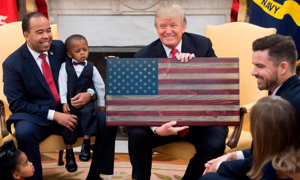 Donald Trump holds an American flag made of wood as he speaks about tax reform alongside ‘ordinary Americans’ in the Oval Office this month.