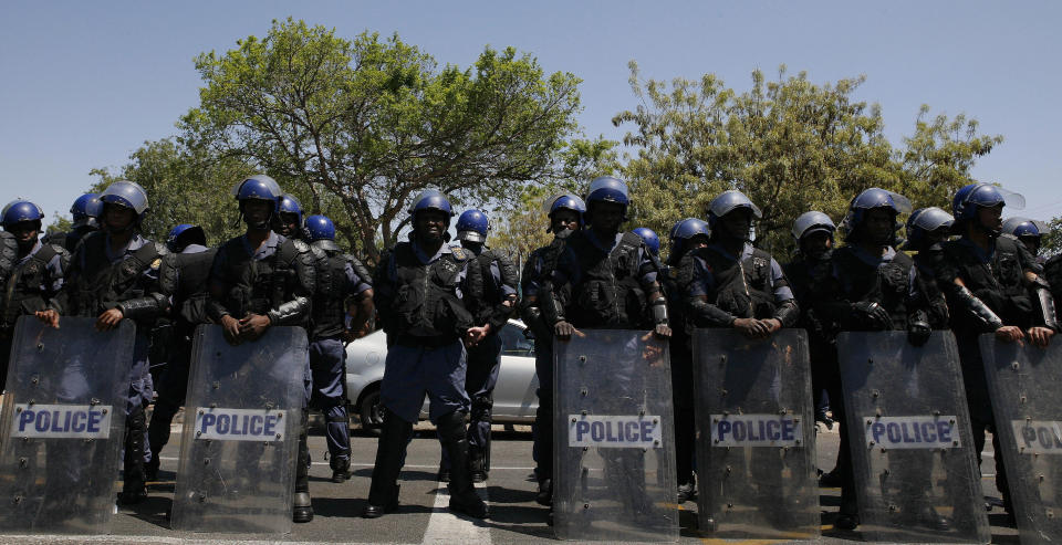 Police officers look on as firebrand politician Julius Malema, unseen, addresses supporters after appearing at the Magistrate’s Court in Polokwane, South Africa, Wednesday, Sept. 26, 2012, on charges of money laundering in connection with an improper government tender awarded to a company his family trust partly owns. (AP Photo/Themba Hadebe)