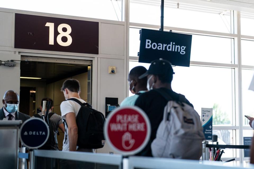 Travelers wait in line to board a flight